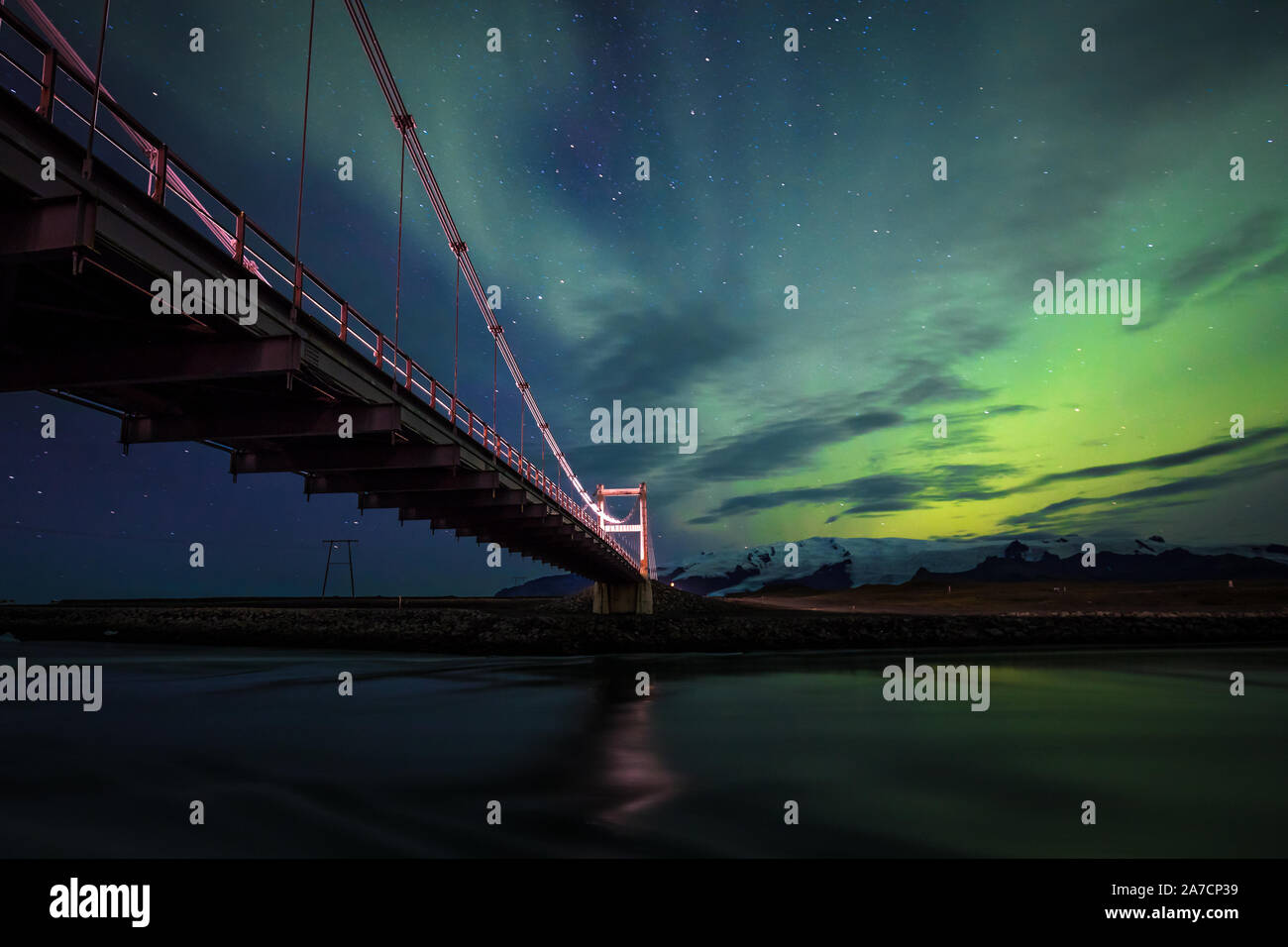 Una noche maravillosa en la laguna glaciar Jökulsarlon en Islandia, disfrutando de la increíble Aurora. He usado el puente para tener una bonita línea líder en el marco... Foto de stock