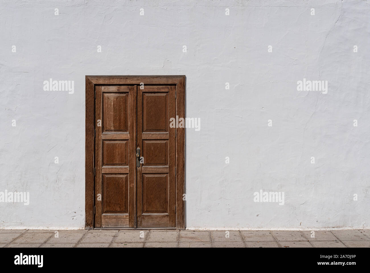 Puerta de entrada de madera marrón rústico en pared blanca desgastada Foto de stock