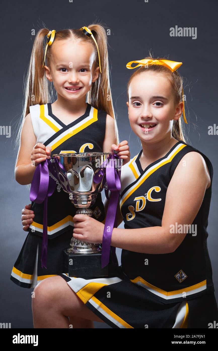 Dos jóvenes caucásicos muchachas vestidas en trajes de baile alegrar y sosteniendo un trofeo. Inglaterra, Reino Unido. Foto de stock