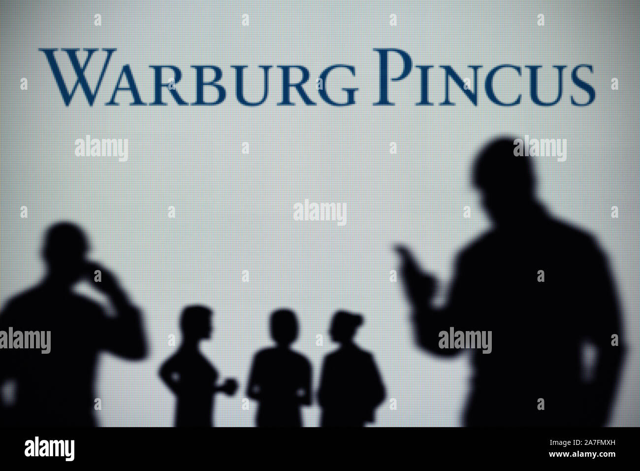 La Warburg Pincus logo es visto en una pantalla LED en el fondo mientras una silueta persona utiliza un smartphone (uso Editorial solamente) Foto de stock