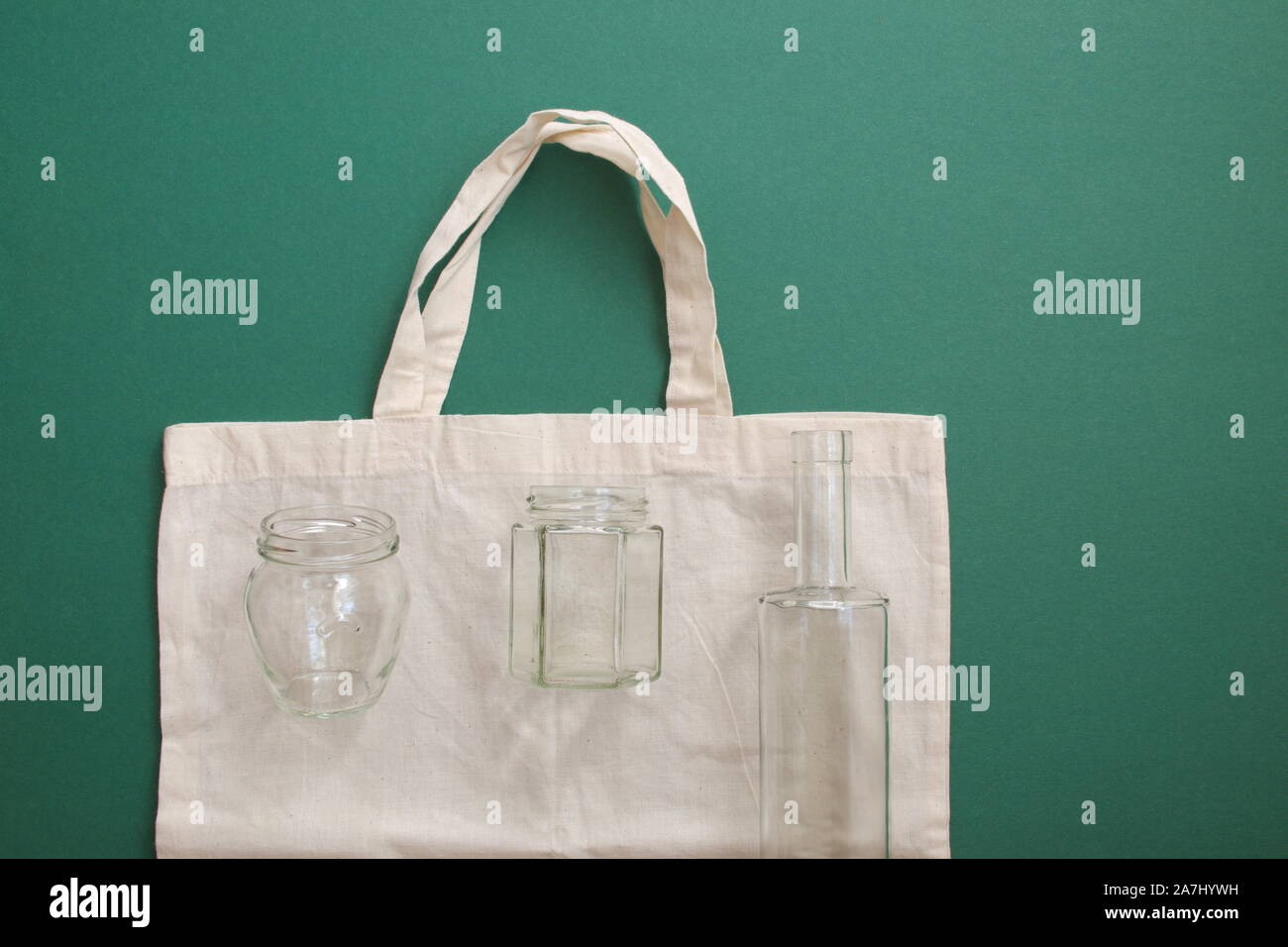 Bolsa de compras reutilizable y botellas de vidrio reutilizable contra el fondo verde Foto de stock