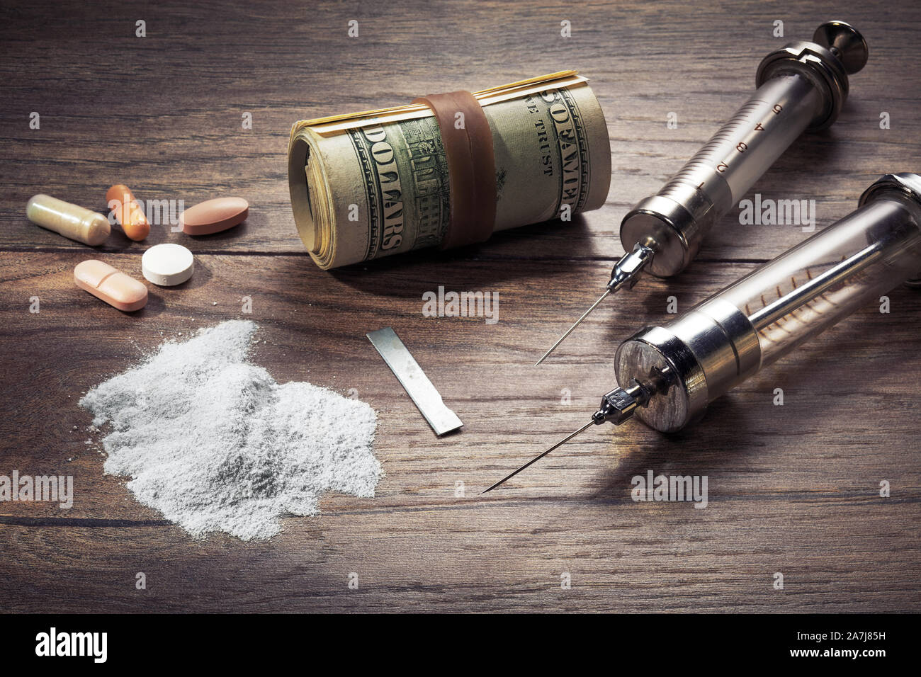 Vintage jeringas, cocaína, pastillas y laminados billetes de dólar sobre la mesa de madera. Concepto de la drogadicción y el narcotráfico. Foto de stock