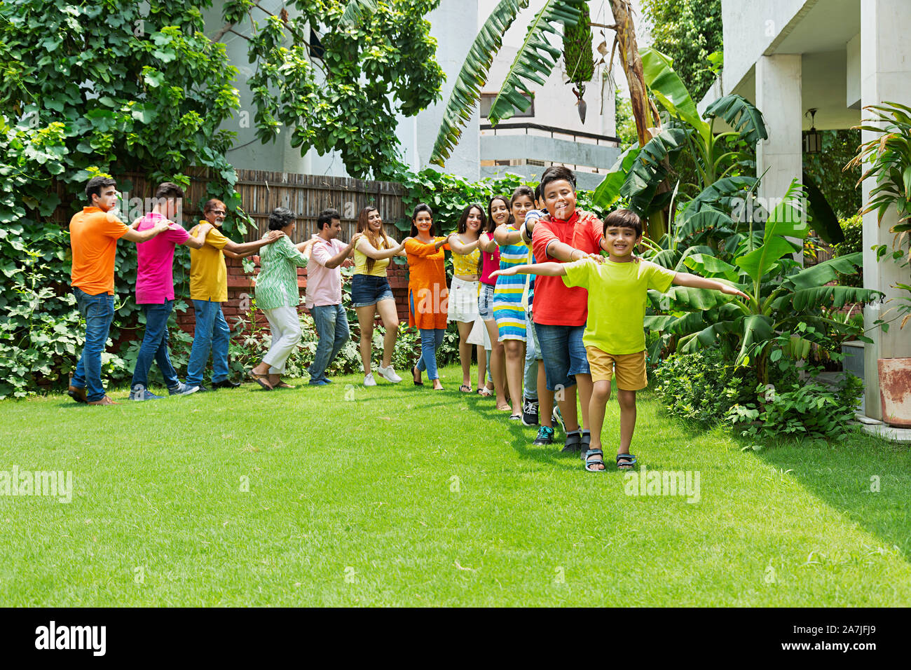 Gran grupo de miembros de la familia india caminando en una línea juntos Having-Fun disfrutar en el parque de su casa Foto de stock
