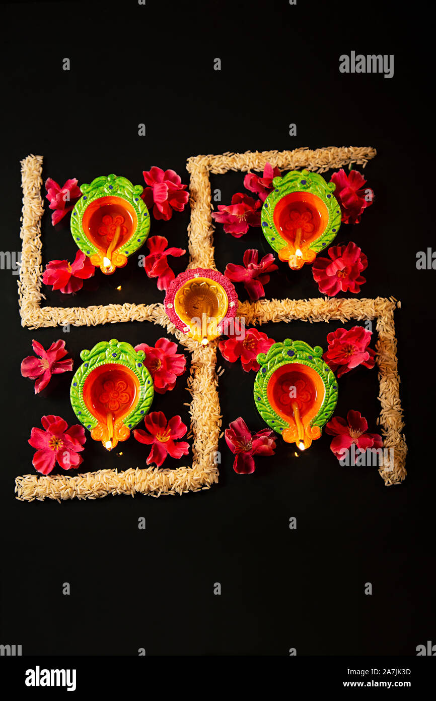 Close-up festival indio Diwali Diyas lámparas de aceite con arroz dispuestos a formar el símbolo swastik Foto de stock