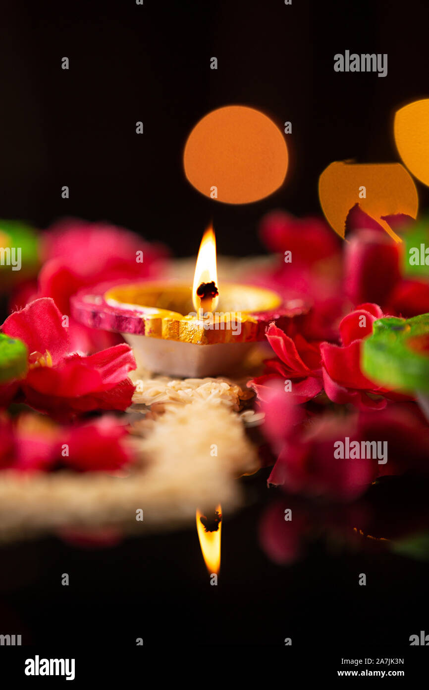 Cerca quema Diya Oil-Lamp con pétalos de rosa durante el Festival de Diwali celebración nadie Foto de stock