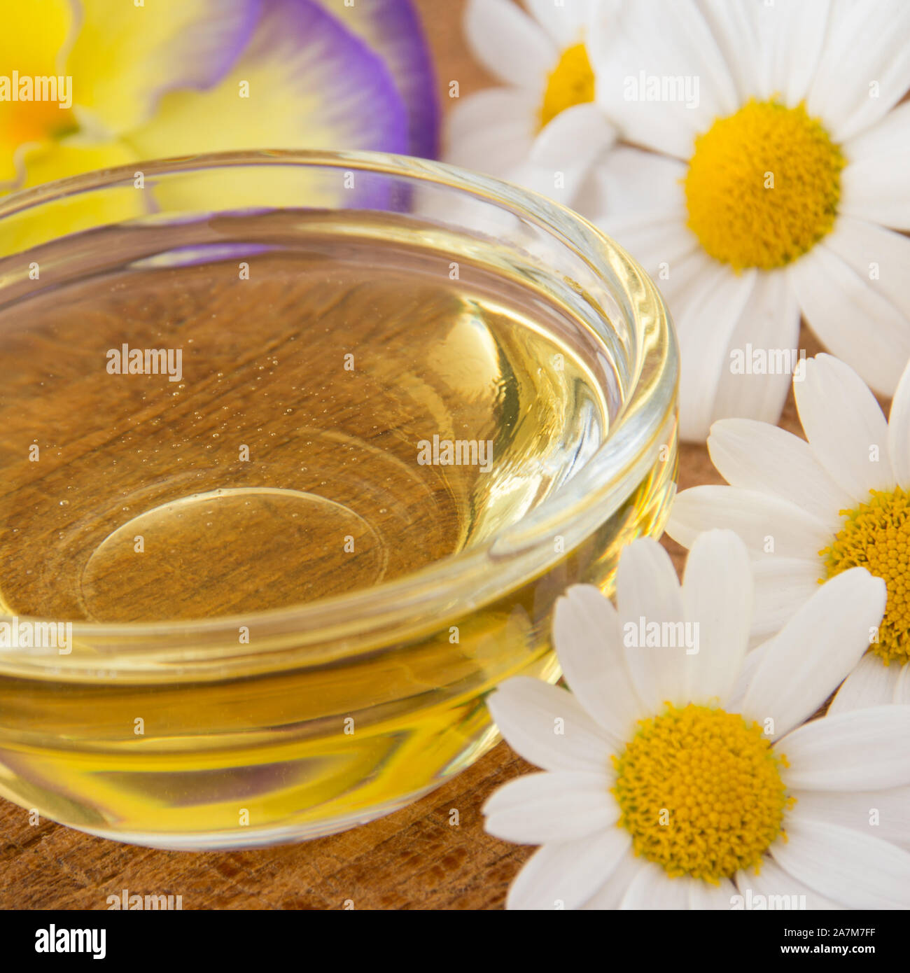 La miel en el tazón de vidrio con flores como fondo Foto de stock