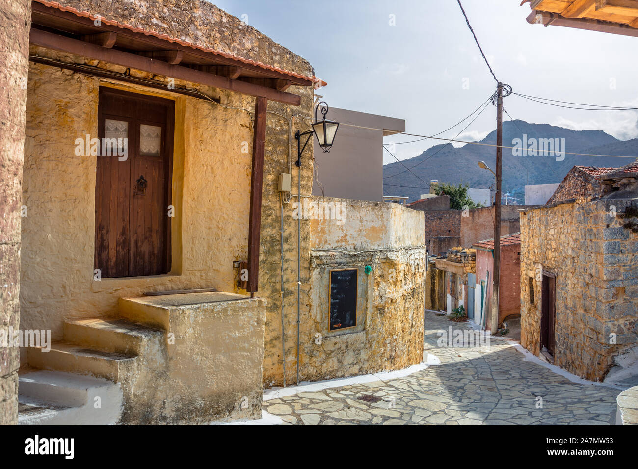 Calle angosta con coloridas casas de piedra en el antiguo pueblo de Pano Elounda, Creta, Grecia. Foto de stock