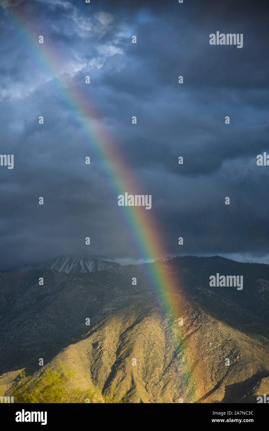 Un arco iris es visible después de una tormenta en Yucca Valley, CA. Foto de stock