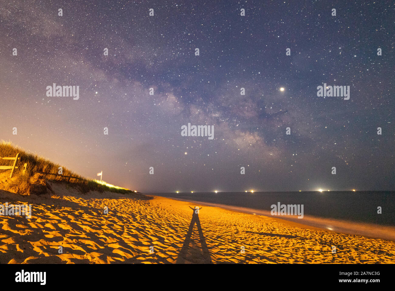 La sombra de un hombre en la arena de la playa, en la galaxia de la Vía Láctea. Foto de stock