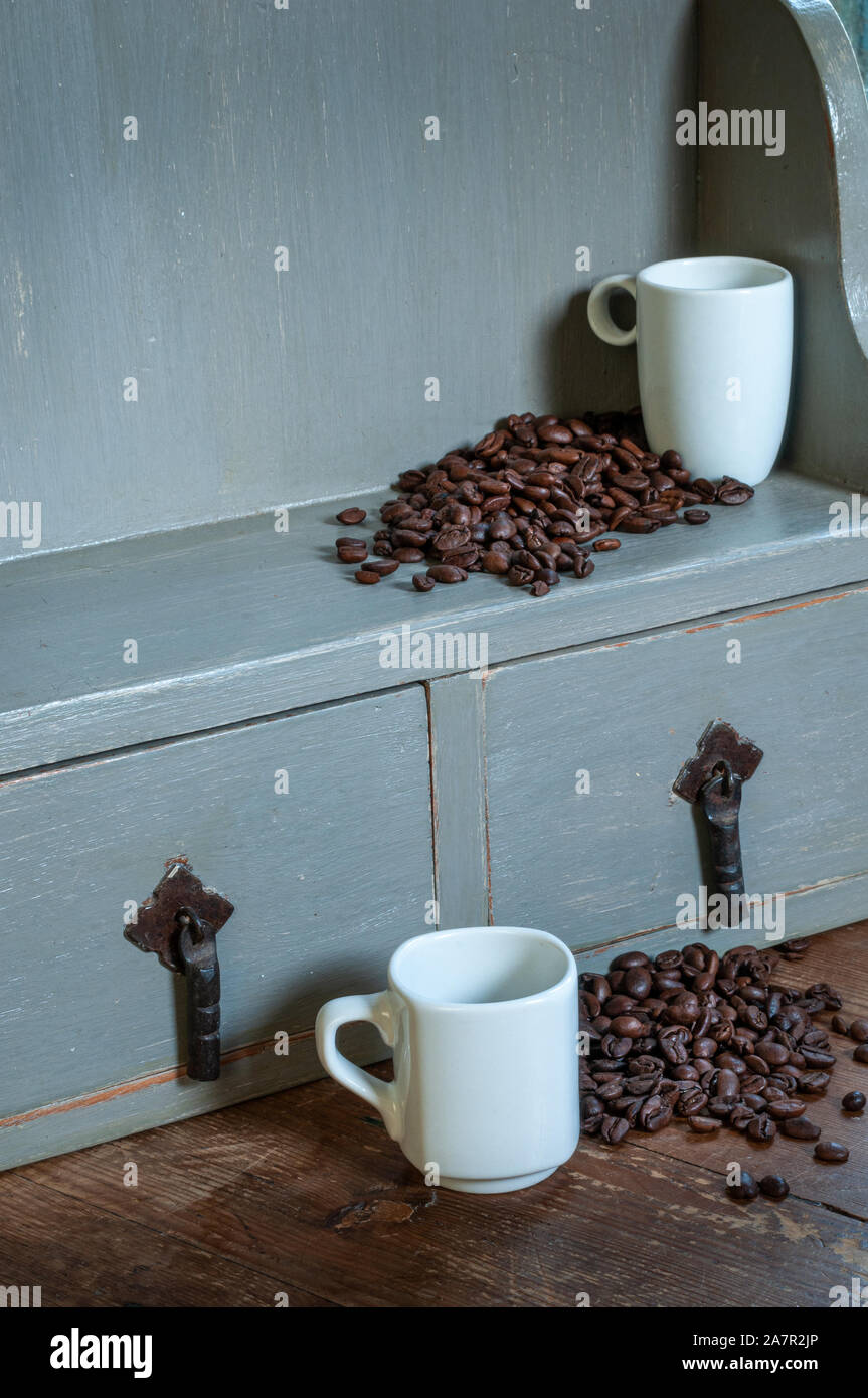 Los granos de café derramándose desde el gris rústico en estante para