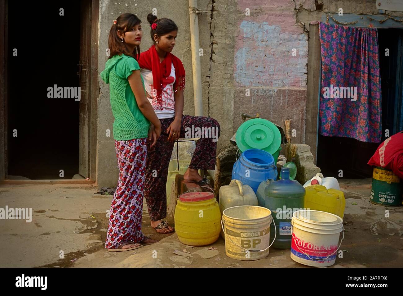 Las mujeres esperan por el camión de agua durante la estación seca en Katmandú, un año después de los terremotos de Nepal de 2015. Foto de stock