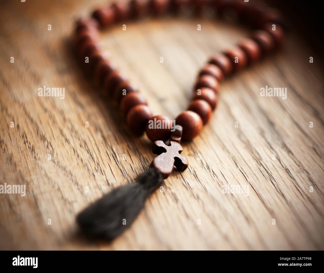 Un santo rosario en caoba con una cruz labrada yace sobre una mesa de  madera, iluminado por la luz del día Fotografía de stock - Alamy