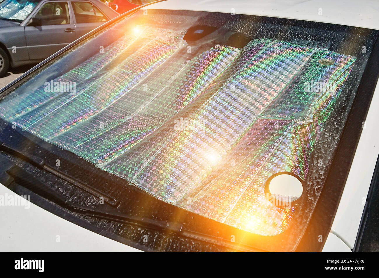 El parabrisas del coche con superficie reflectante de protección solar  interior de coche aparcado en la calle con rayos de sol. Método para  proteger calentado por los rayos del sol alquiler Fotografía