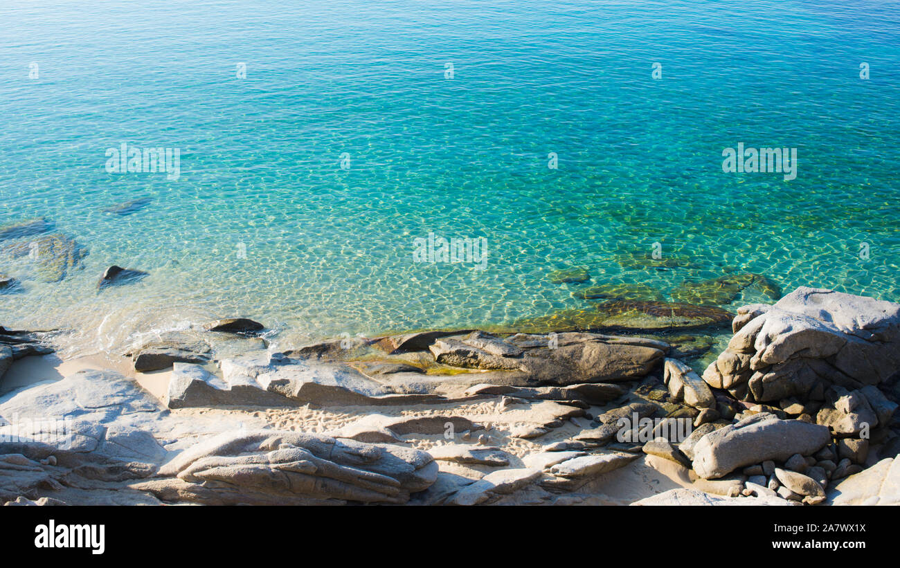 Playa rocosa orilla con prístino azul verde claro del agua de mar. Foto de stock