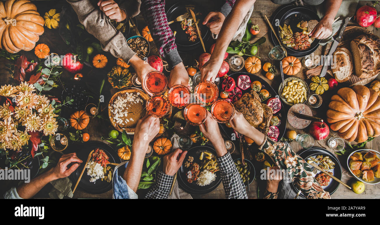 Familia celebrando el Día de Acción de Gracias con comida y vino rosado de Otoño Foto de stock