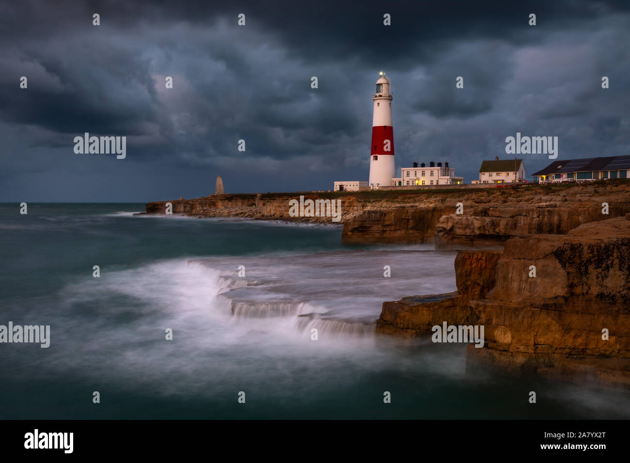Portland Dorset, Inglaterra tormentoso cielo de Portland Bill faro, como olas que rompen en la costa rocosa. Foto de stock