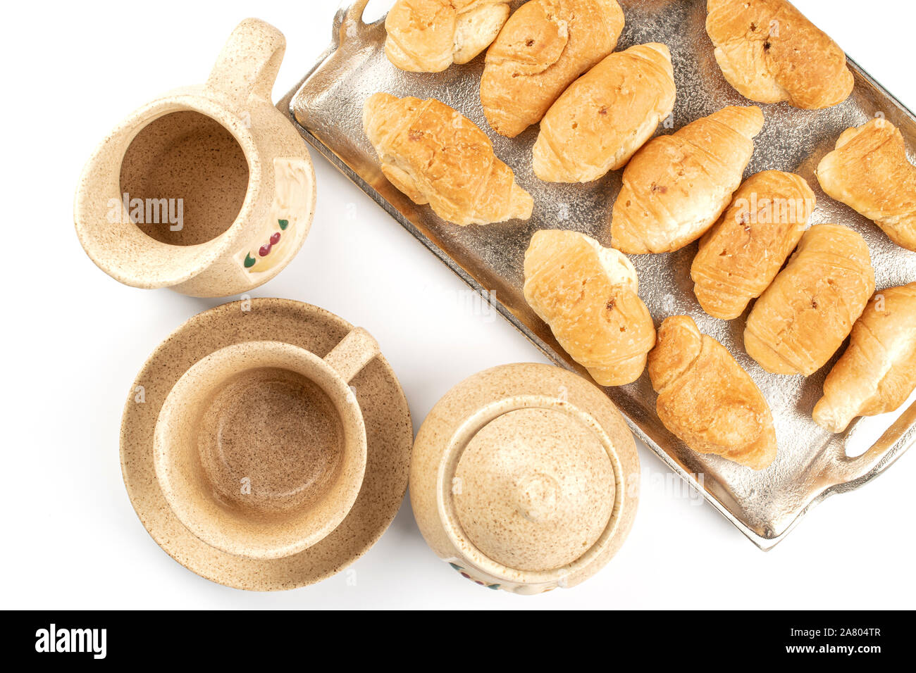 Mucho de todo mini croissants recién horneados en la bandeja con la copa , Sugar Bowl y jarra cerámica flatlay aislado sobre fondo blanco. Foto de stock