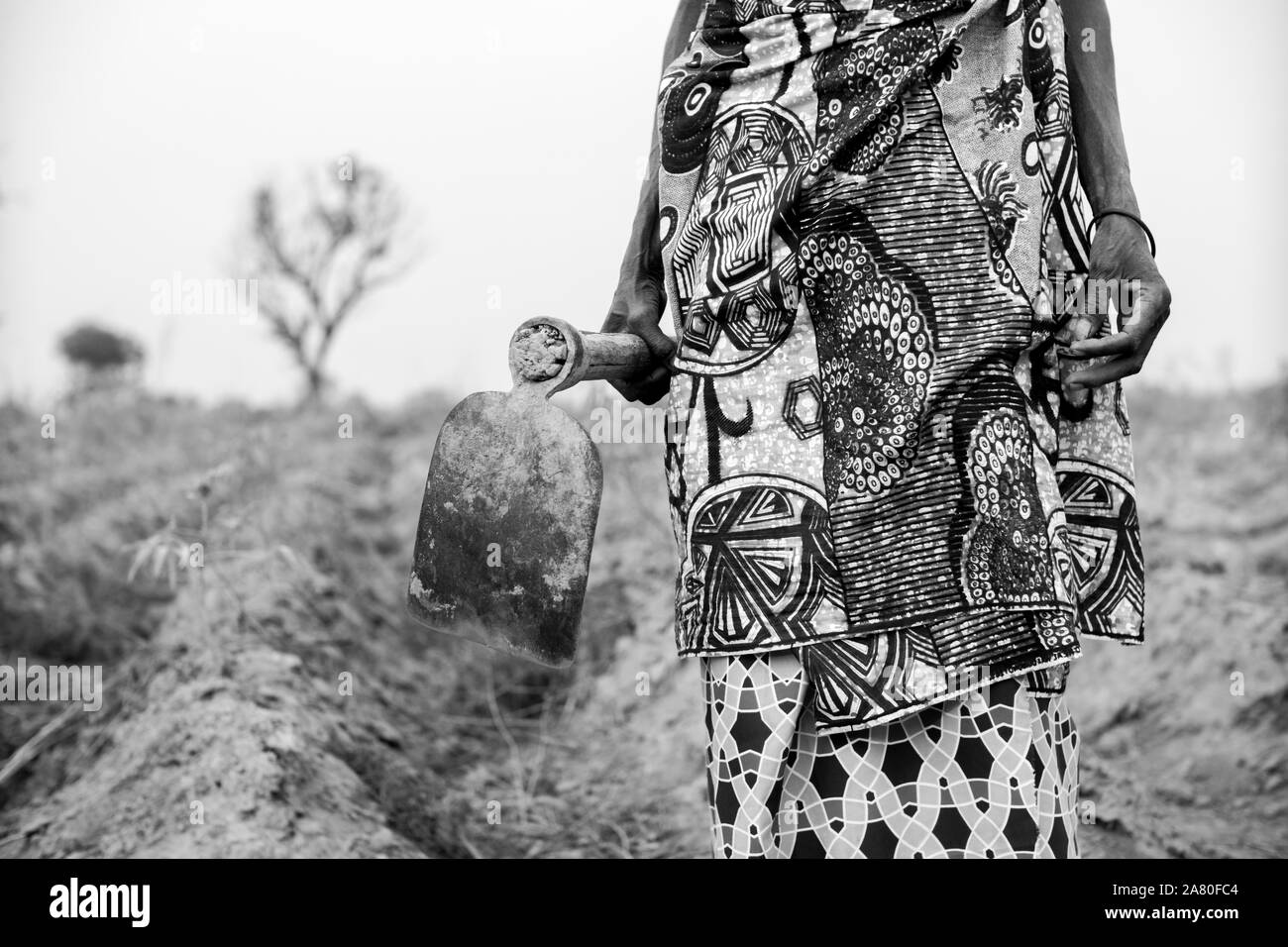 La agricultora local vestida con coloridas telas africanas. Blanco y negro. Foto de stock