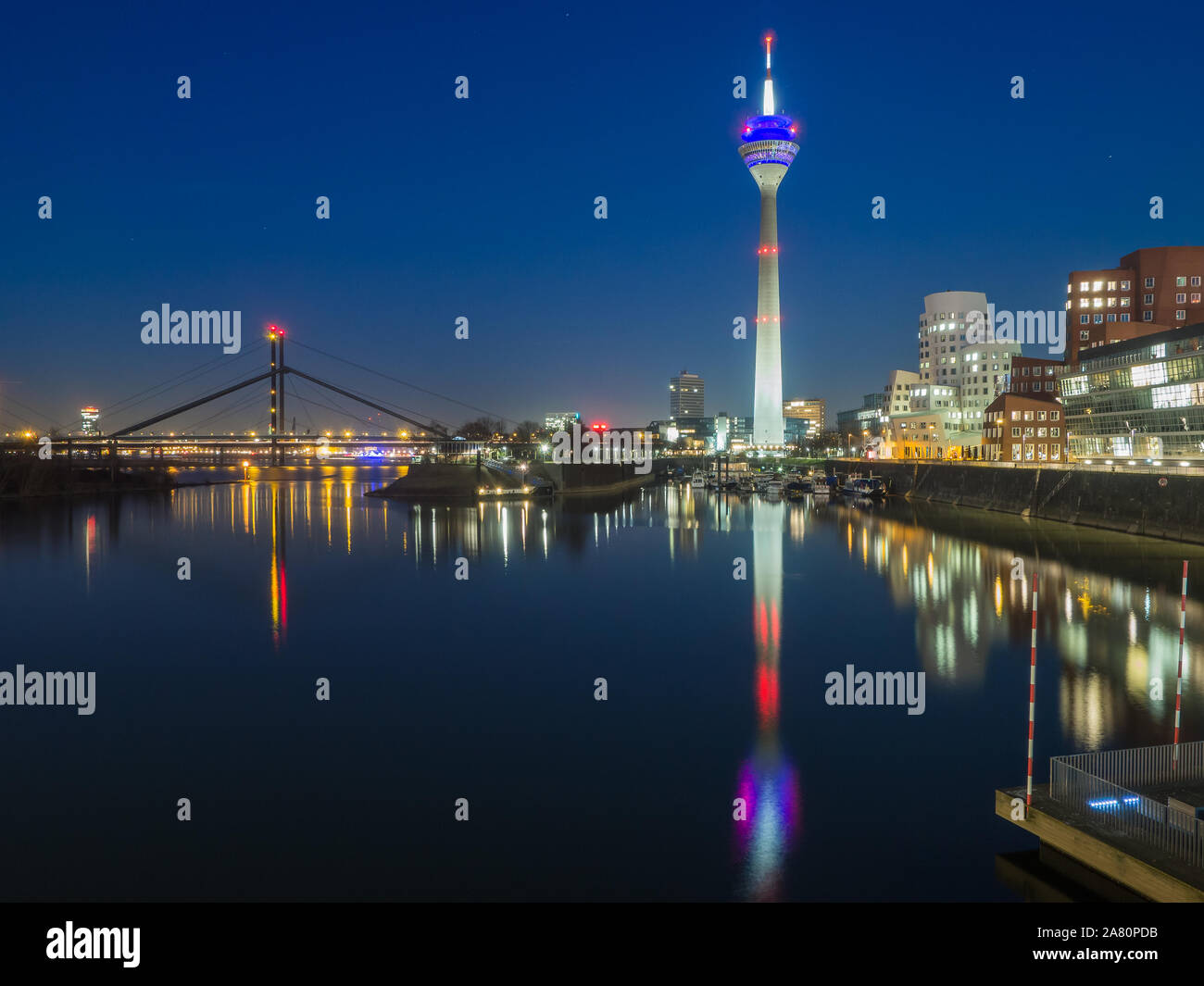 Por la noche desde el Düsseldorf Hafen, con Rheinturm, Neuer Zollhof edificios de Frank Gehry y el Fussgängerbrücke. Centro de negocios en Europa. Foto de stock