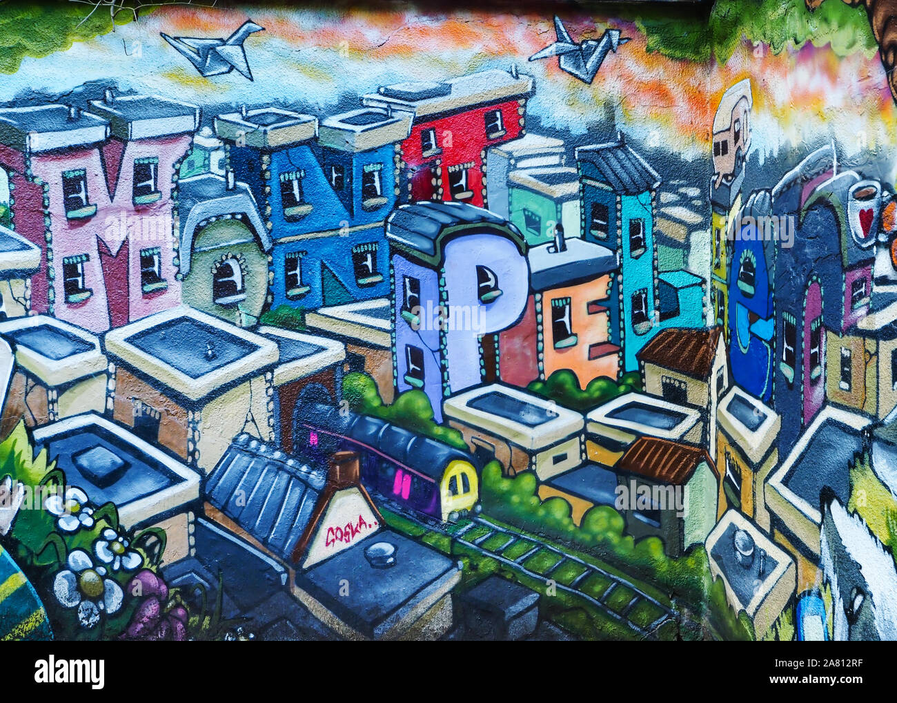 Parte de un arte de la calle mural del artista Hobo silenciosa en Montpelier railway station en Bristol mostrando coloridas casas de deletrear la ubicación Foto de stock