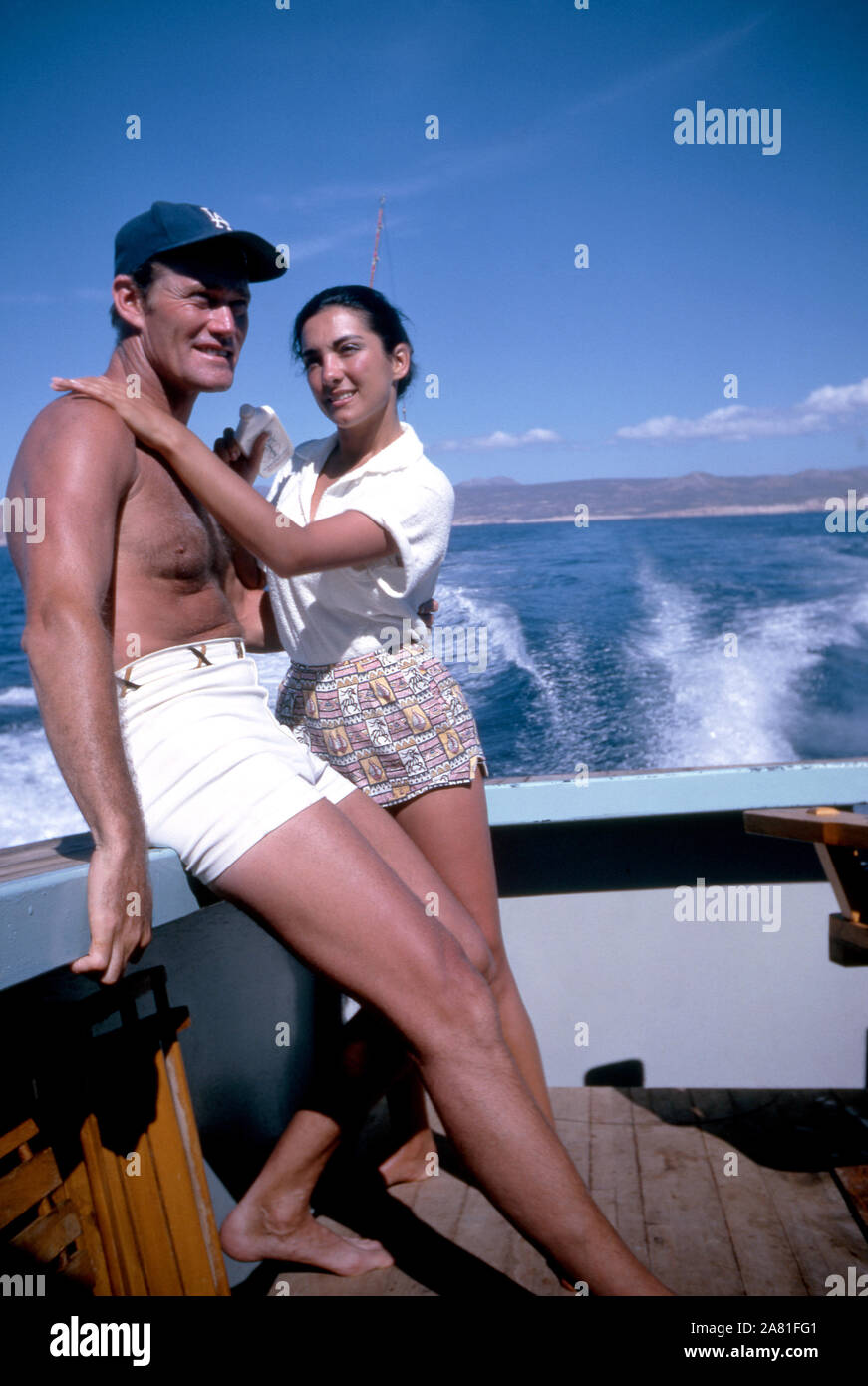 BAJA CALIFORNIA, MÉXICO - JUNIO DE 1962: el actor y ex jugador de béisbol Chuck Connors (1921-1992) y la actriz prometido Kamala Devi (1934-2010) Relájese en un barco durante un viaje de pesca alrededor de junio de 1962, en Baja California, México. (Foto por Hy Peskin) (número de registro: X8569) Foto de stock