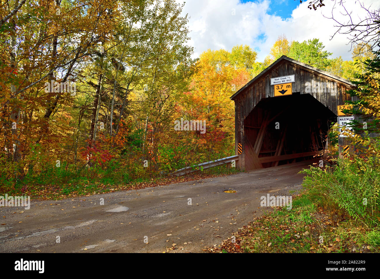 Una imagen de un paisaje otoñal icónico puente cubierto cruzando la trucha Creek, en un camino de ripio rural cerca de Sussex de Nueva Brunswick, Canadá. Foto de stock