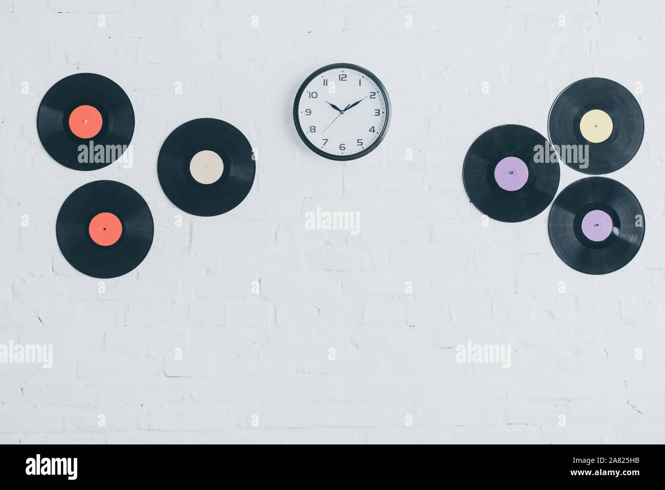 Los discos de vinilo y redondo reloj de pared de ladrillo blanco. Foto de stock