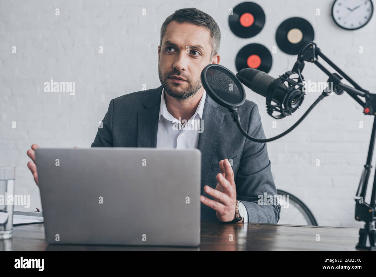 Apuesto locutor de radio gesticulando mientras habla en el micrófono en el  lugar de trabajo cerca de laptop Fotografía de stock - Alamy