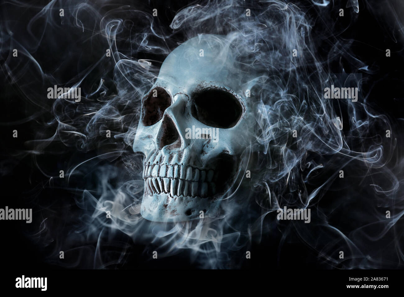 Cráneo humano con humo sobre fondo oscuro Foto de stock