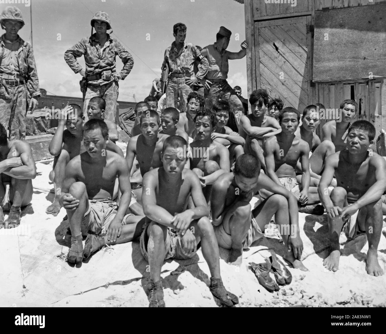 Los prisioneros en el extremo del muelle de Tarawa esperando transporte a un barco para seguir interrogándolo Foto de stock