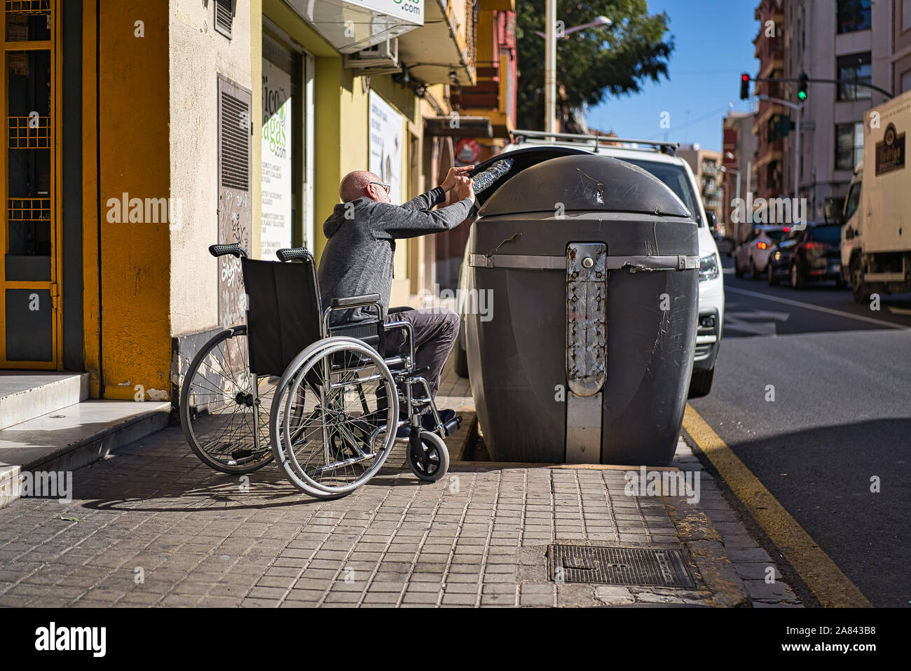 Personas discapacitadas en silla de ruedas recogiendo una botella de  plástico transparente arrojado y abandonado en el suelo para tirarlo en el  contenedor de reciclado de basura Fotografía de stock - Alamy