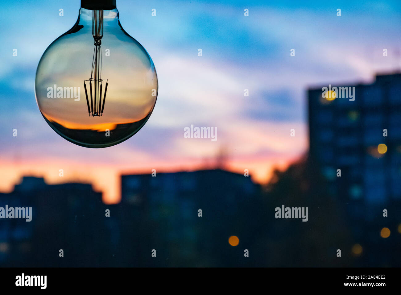 Desenfoque hermoso atardecer en una bombilla. Puesta de sol de fondo. Concepto de electricidad. La hora de la tierra. El consumo de energía y la conservación del medio ambiente Foto de stock