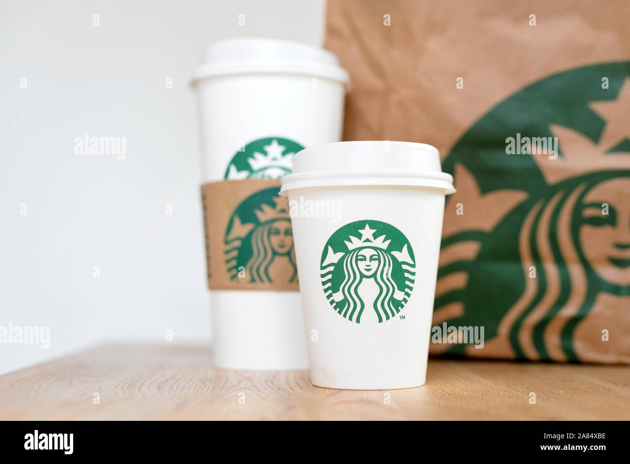 KIEV, Ucrania / Noviembre 06, 2019: café de Starbucks para llevar tazas con bolsa de papel sobre la mesa del contador de madera. American global café y café Foto de stock