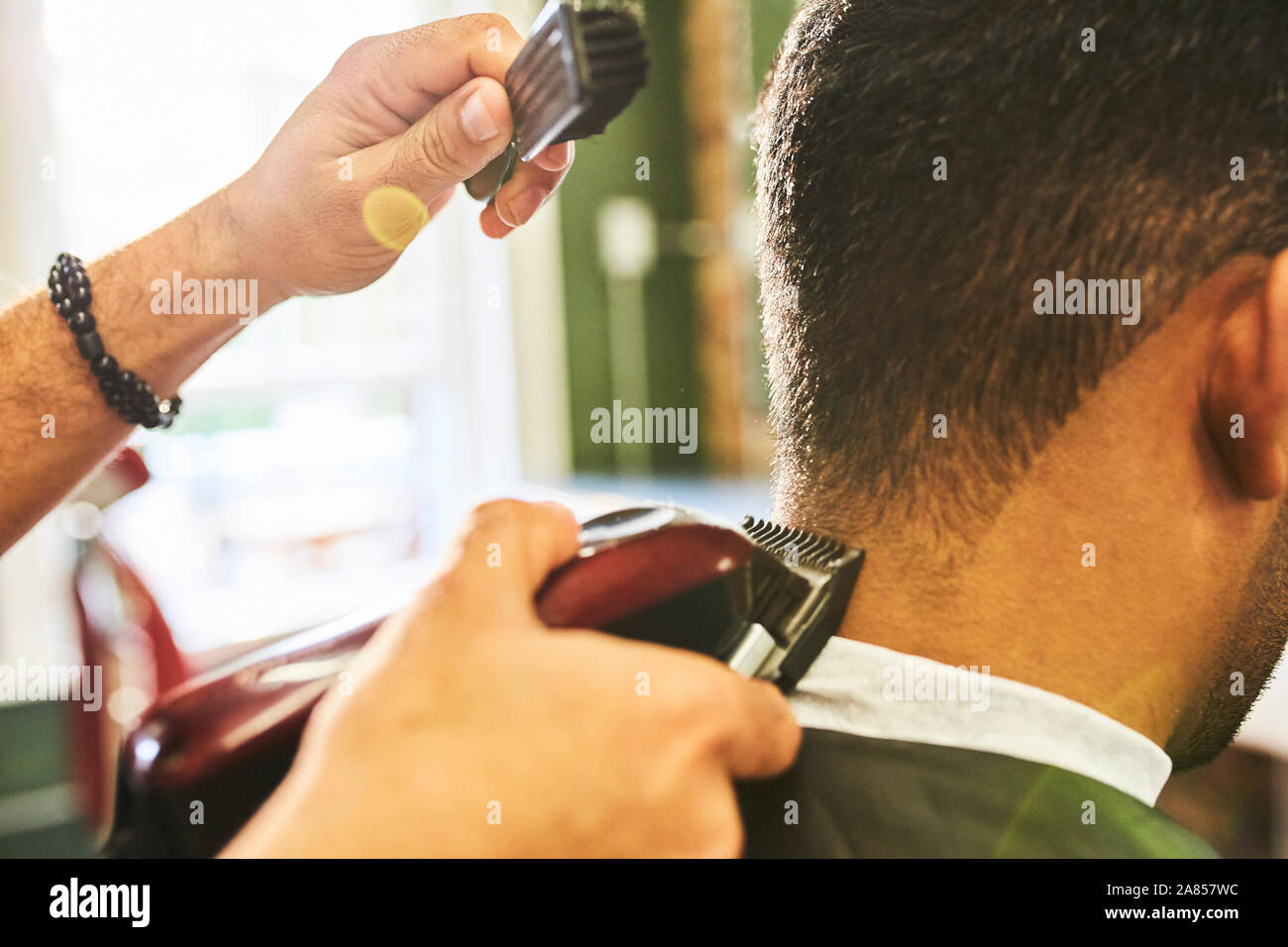 Cerca de peluquería masculina con recortador de pelo de cliente Foto de stock