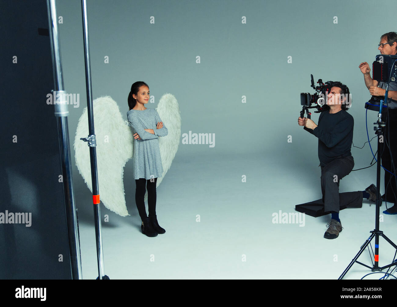 Chica en alas de ángel posando para los fotógrafos durante la sesión fotográfica en studio Foto de stock