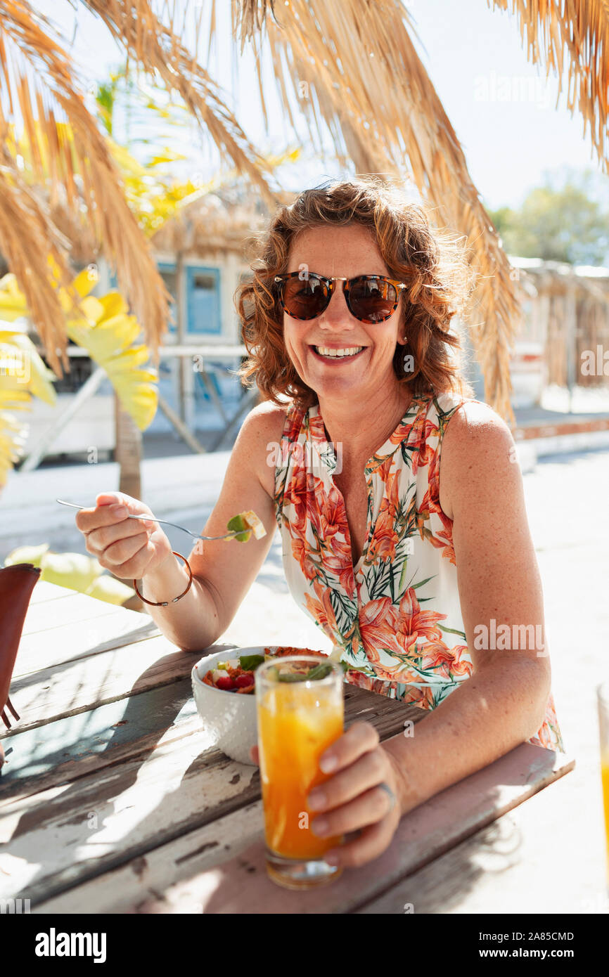 Retrato mujer felices comiendo y bebiendo en sunny beach bar Foto de stock