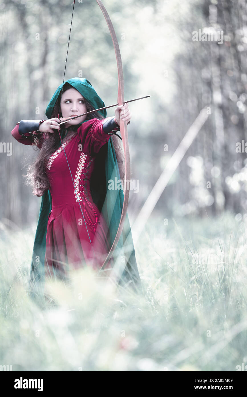 Un elfo arquero con un arco en el bosque Foto de stock