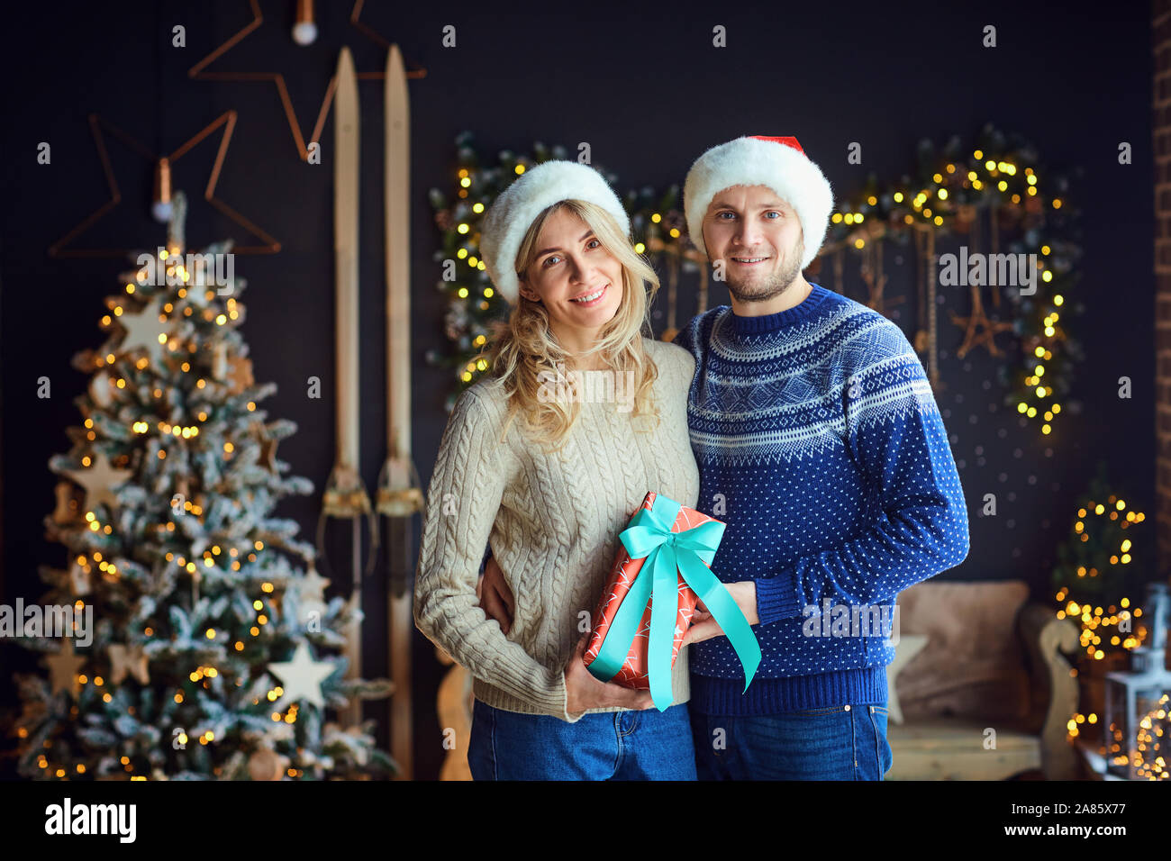 El esposo y la esposa con regalos en una sala en Navidad. Foto de stock