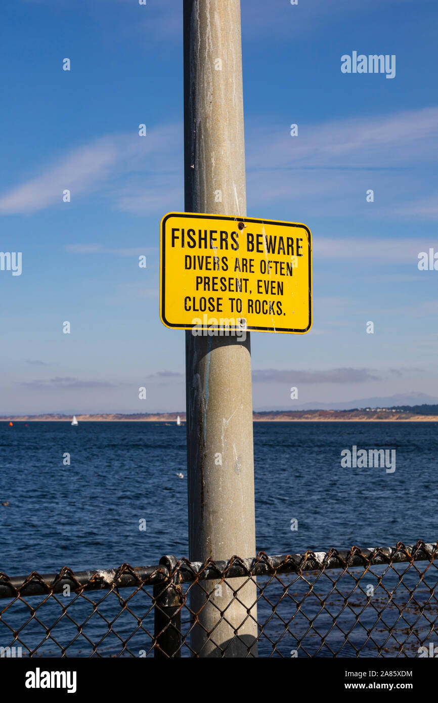 "Cuidado con los pescadores. Los buzos con frecuencia están presentes, incluso cerca de las rocas" firmar en el post, la Guardia Costera pier, Monterey, California, Estados Unidos de América. Foto de stock