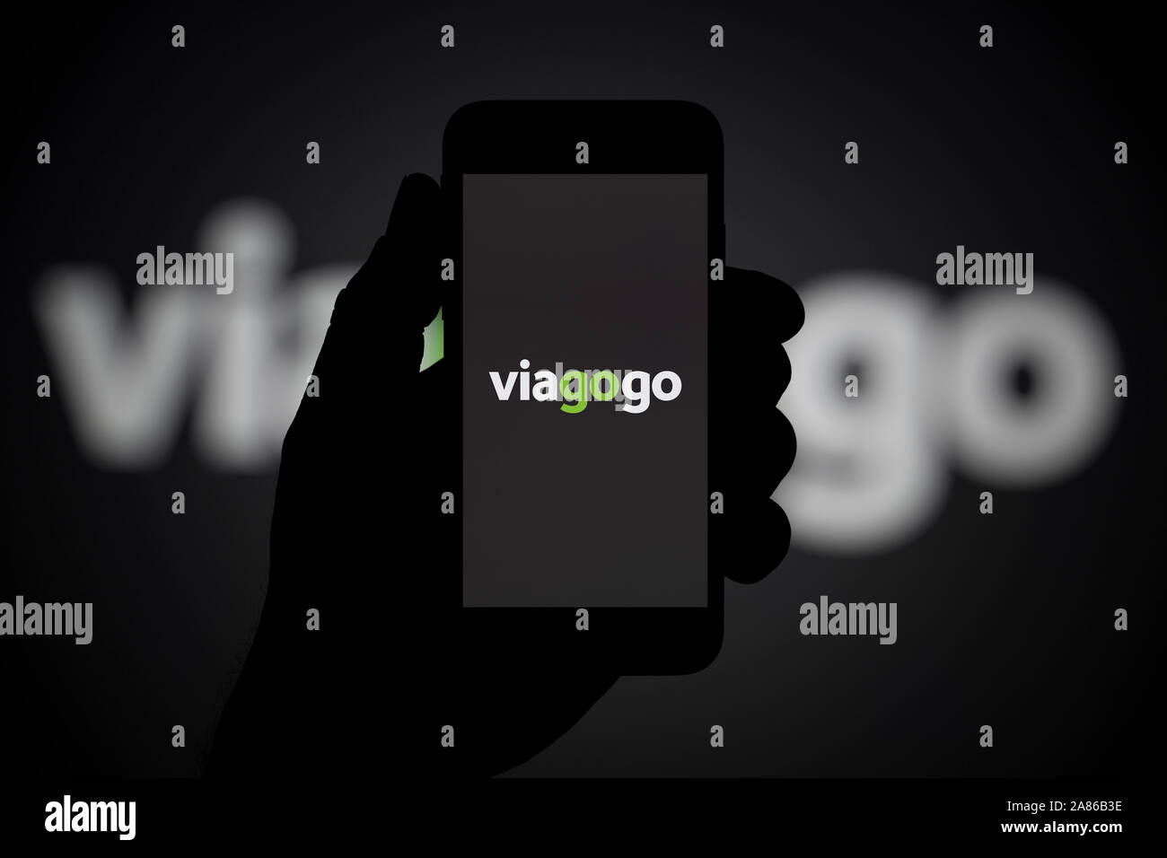 Un hombre mira el iPhone que muestra el logotipo de Viagogo, con el mismo logotipo en el fondo (sólo para uso editorial). Foto de stock