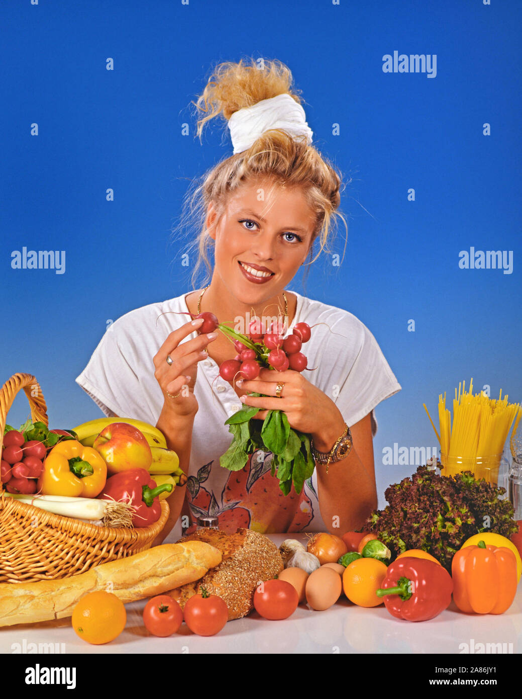Blonde Frau zum Fruehstueck Radieschen isst, Foto de stock