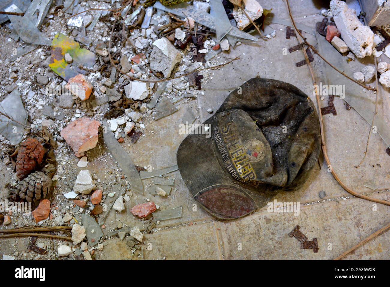 Escombros en el piso del edificio abandonado con viejos desechados Pittsburgh Steelers (fútbol) alcanzó un máximo gorra de béisbol Foto de stock