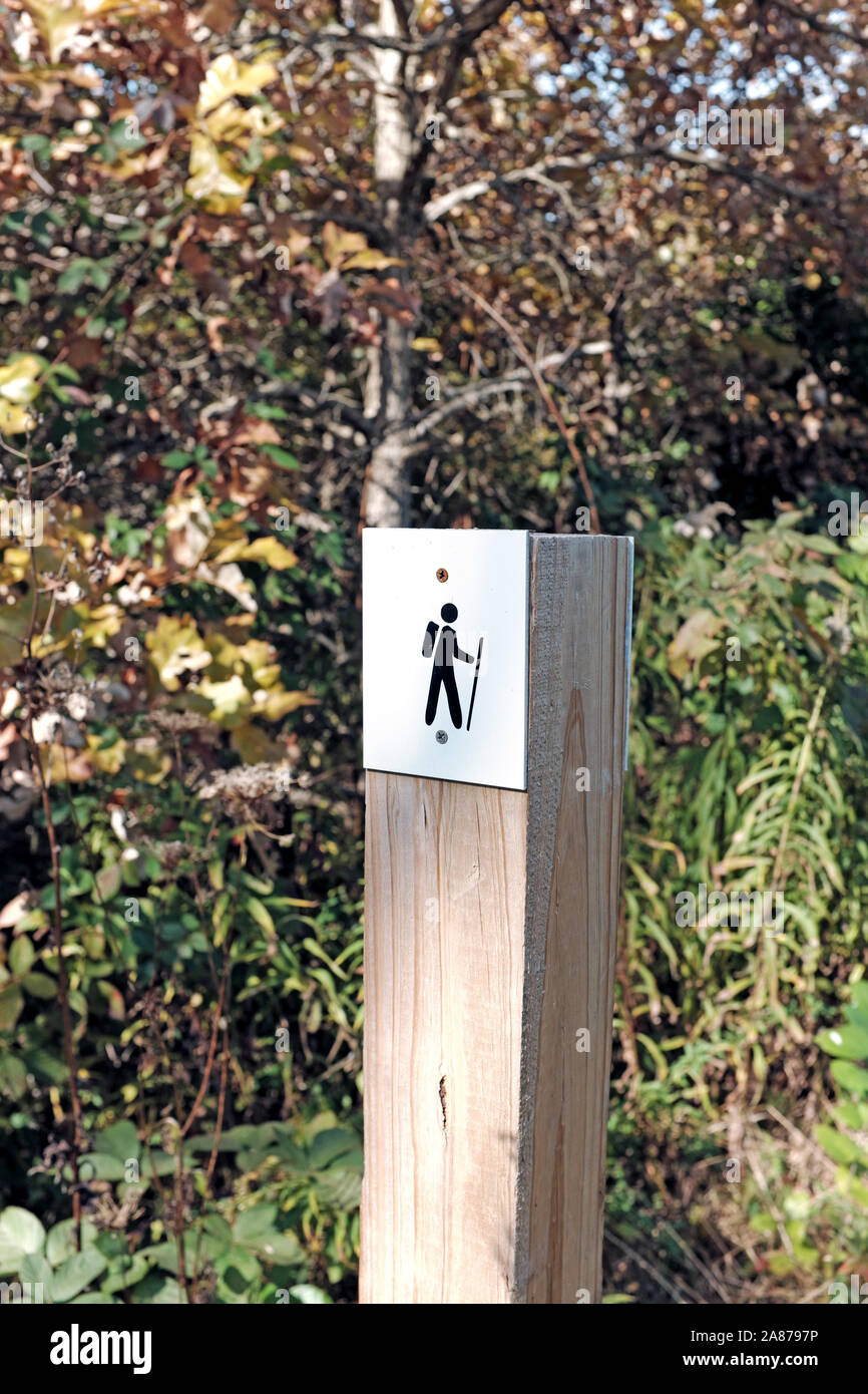 Poste de madera con caminante caricatura indicando el existnece de una ruta de senderismo en la naturaleza en el noreste de Ohio. Foto de stock