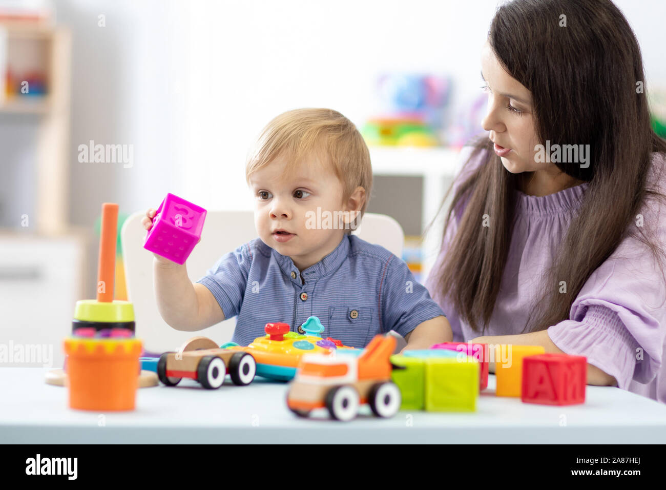 Madre y bebé niño jugar con juguetes en la sala de párvulos Foto de stock