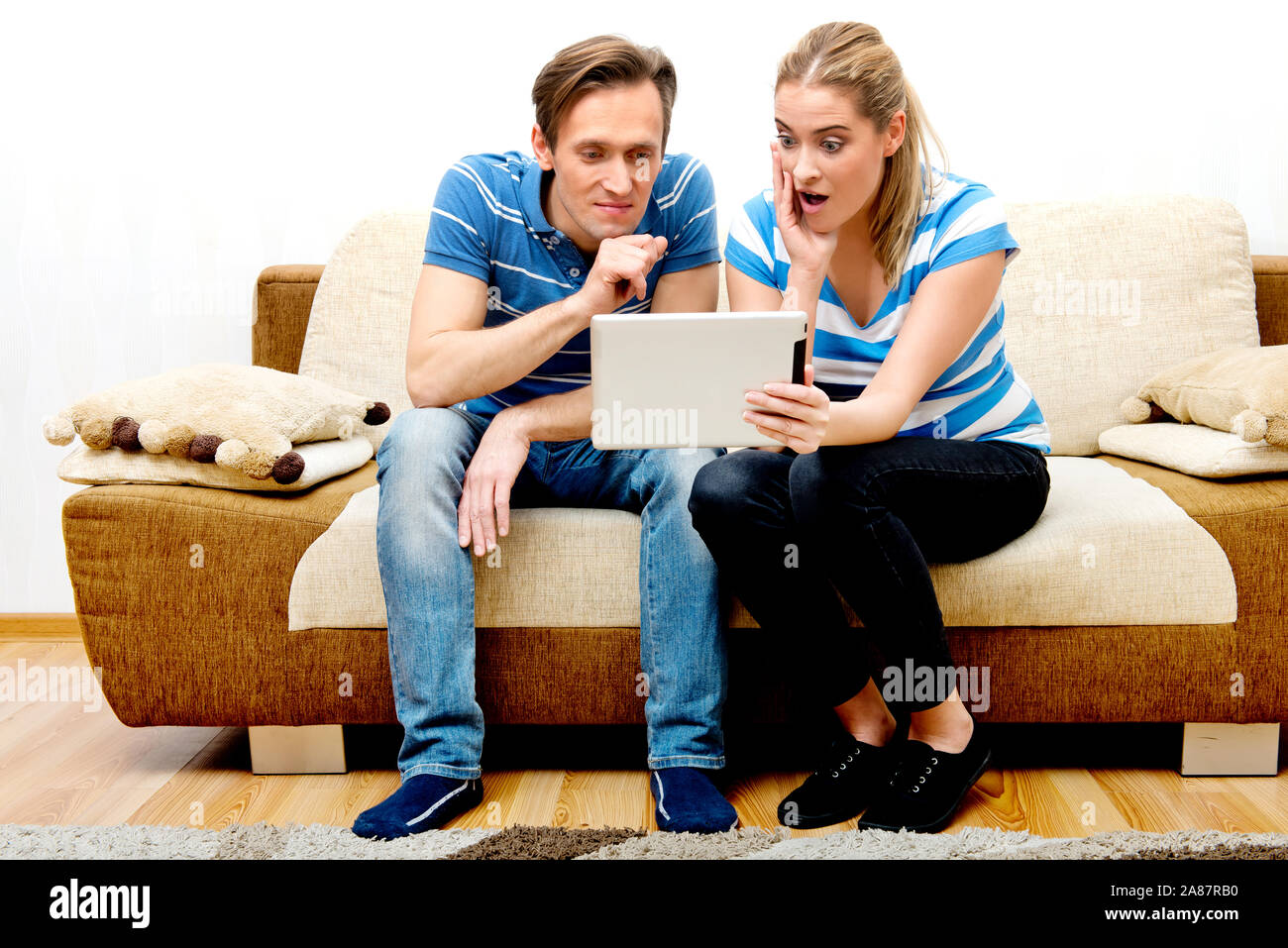Pareja sentada en un sofá y viendo la película sobre la tableta. Transmisión multimedia en internet. Foto de stock