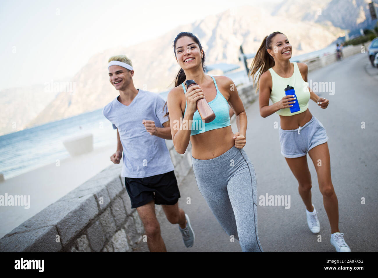 Grupo de jóvenes amigos corriendo a la intemperie en seaside Foto de stock