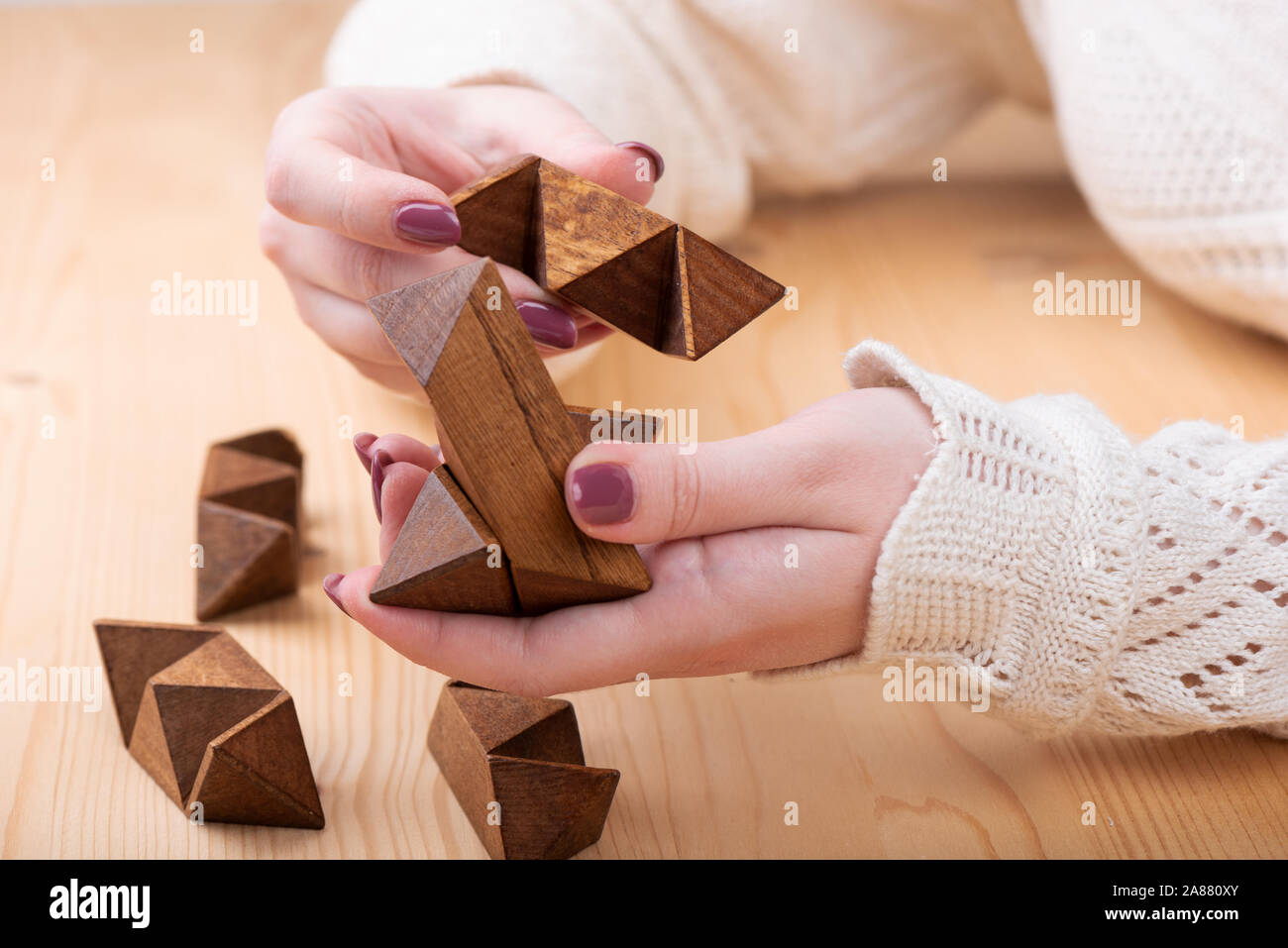 rompecabezas dodecaedro de forma de en las manos de una Doce caras pequeña estrella en forma dodecaedro sobre una mesa de madera. Concepto de puzzle Fotografía de stock -