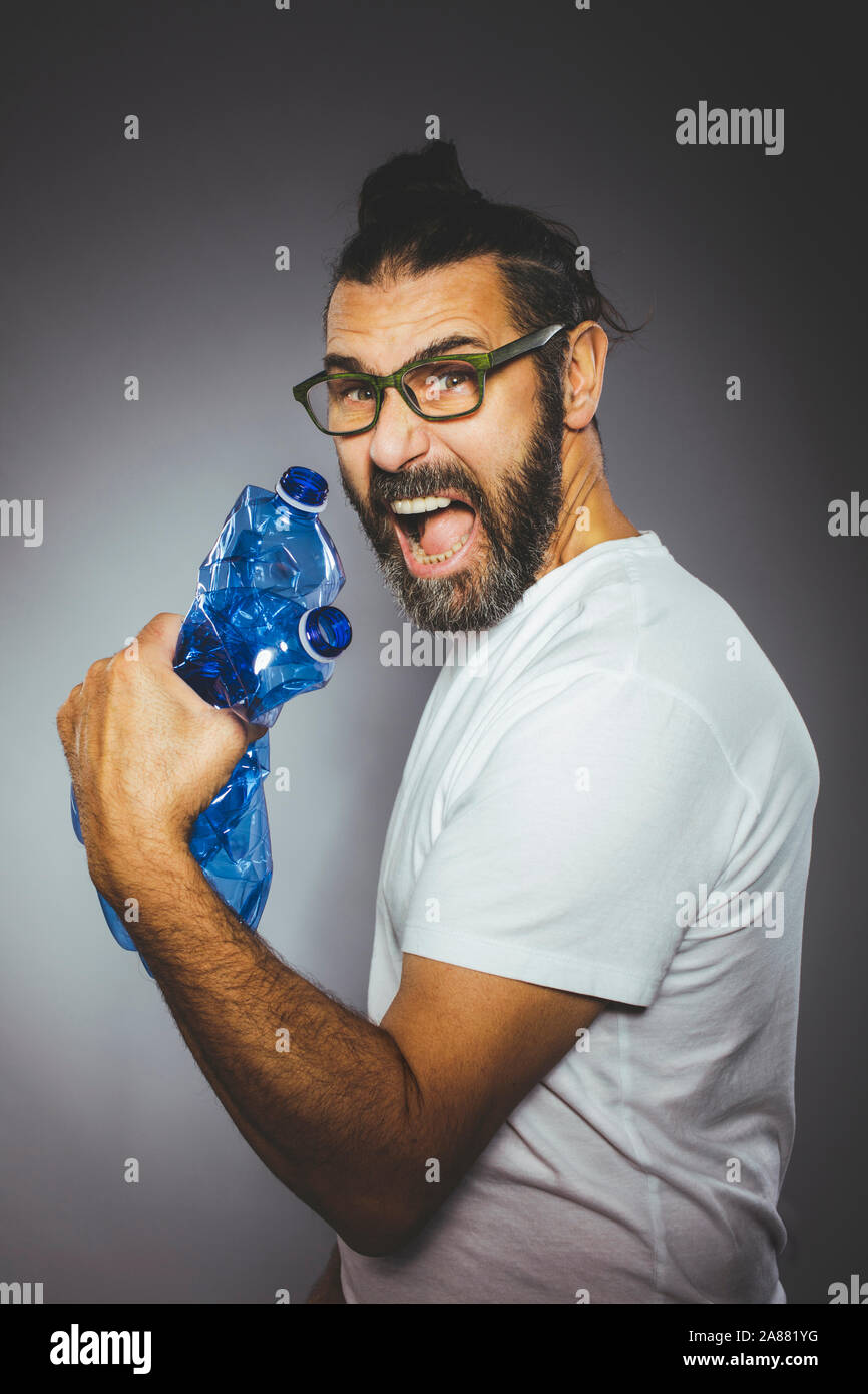 Hombre con barba y gafas es la celebración de botellas de plástico. Concepto de reciclaje y uso excesivo de plásticos. Foto de stock