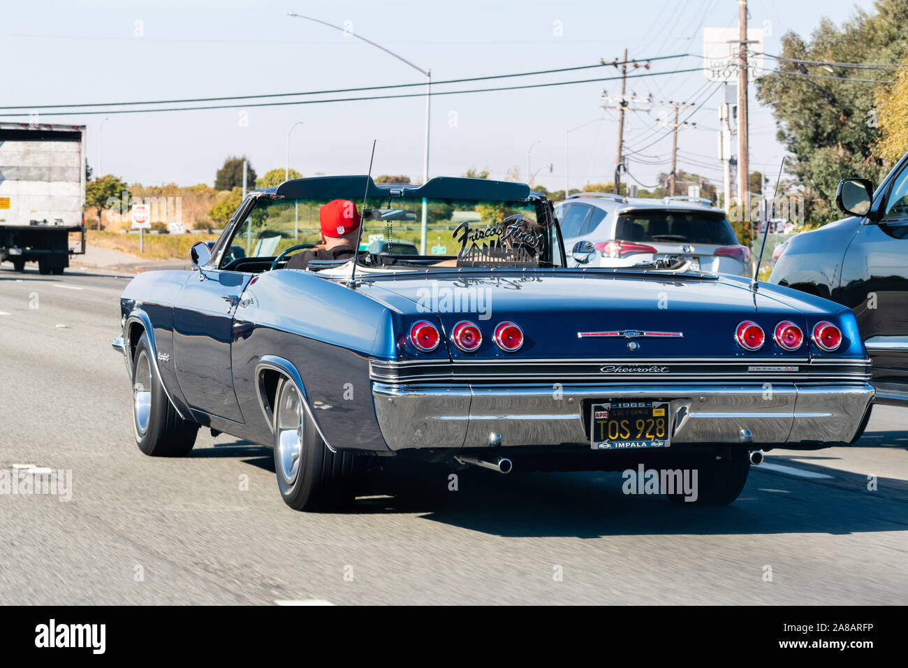 Oct 26, 2019 San Francisco / CA / US - 1965 Chevrolet Impala SS conduciendo en la autopista; Frisco's Finest car club logotipo mostrado en el coche Foto de stock