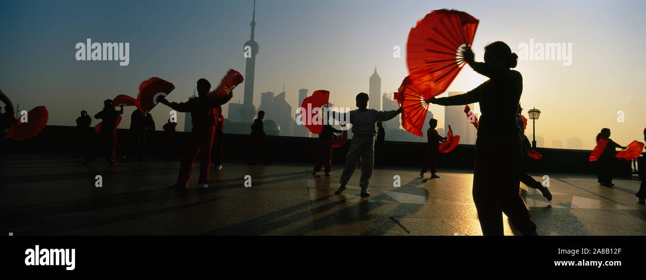 Silueta de un grupo de gente bailando en frente de Pudong, el Bund, Shanghai, China Foto de stock
